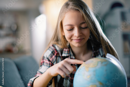 Portrait of cute little girl in living room looking globe. Pretty girl exploring world. 