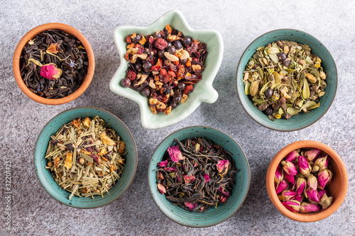Assortment of dried herbal tea in ceramic bowls. Top view, close up. Food background.