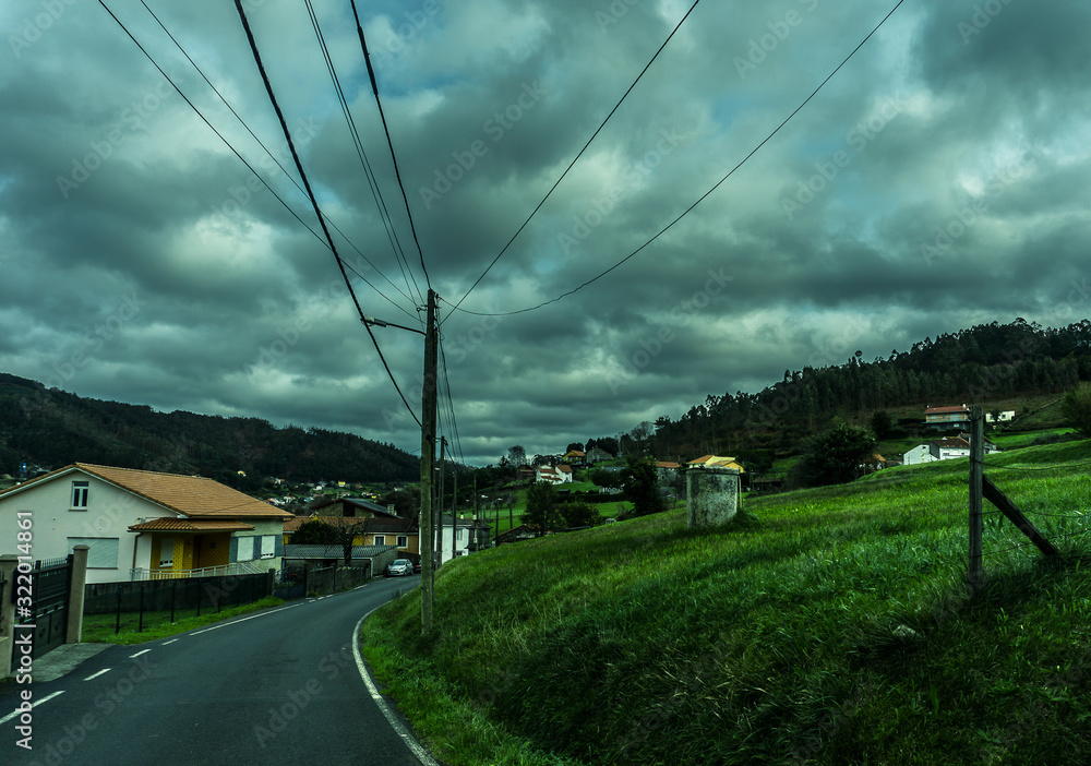 Una carretera de un pueblp con campo al lado.