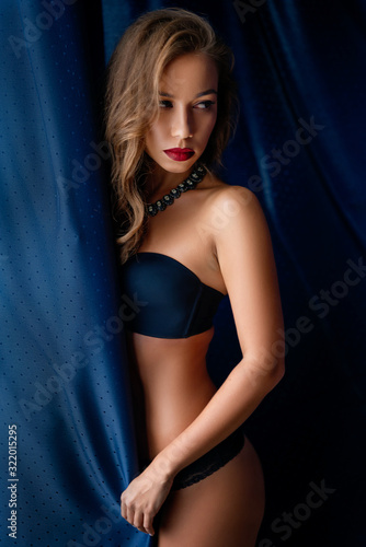 sexy young woman in black lingerie stands at the window wrapped in a curtain © Екатерина Переславце