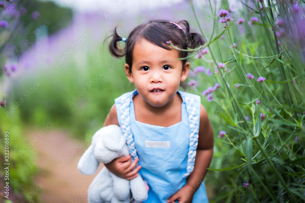 Cute little girl playing at verbena flower field.