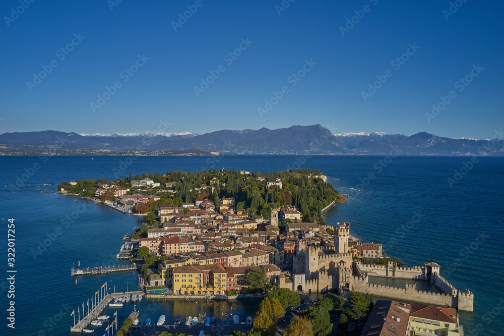 Unique view. Aerial photography, the city of Sirmione on Lake Garda north of Italy. In the background is the Alps in the snow. Resort place. Aerial view. Autumn-winter season