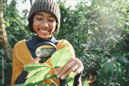 Asian little girl exploring the nature with magnifying glass and happy smile In the midst sunlight in the morning