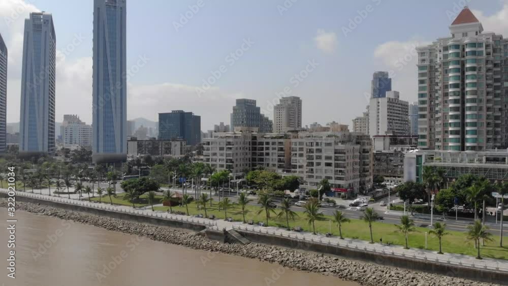 Backwards aerial reveal shot of Zhuhai coastline skyscrapers and cityscape on clear sunny day Backwards aerial reveal shot of Zhuhai coastline skyscrapers and cityscape on clear sunny day