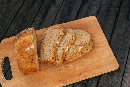 Fresh homemade bread with sunflower seeds, isolated on a wooden background. Side view, top view, close-up view. Ears of wheat, rye.
