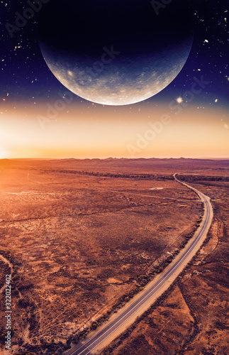 Book cover template. Unreal landscape - dark planet over road winding through desert landscape at sunset. Elements of this image are furnished by NASA