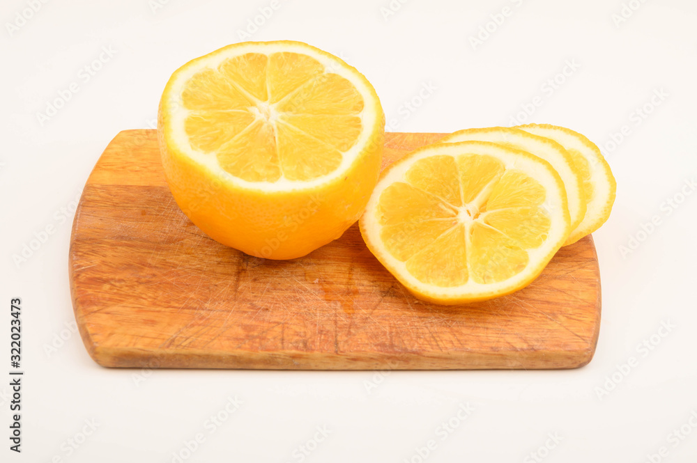 Ripe yellow sliced lemon on a Board on a white background. Close up. Ripe yellow sliced lemon on a Board on a white background. Close up.