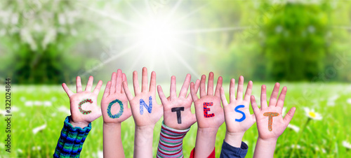 Children Hands Building Colorful Word Contest. Sunny Green Grass Meadow As Background