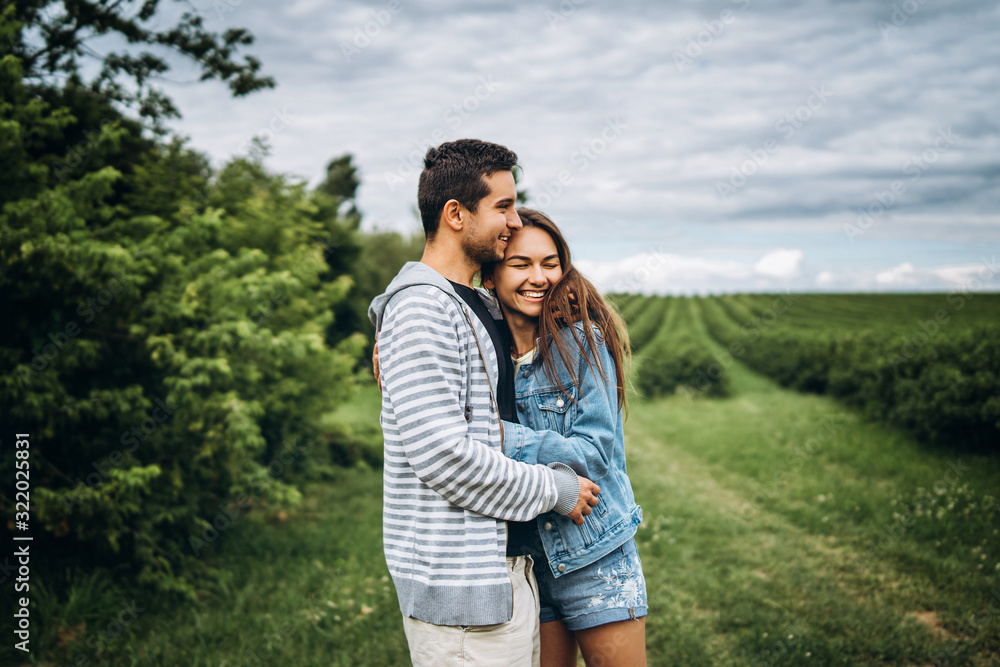 Young loving couple, woman and man, gently hugging with eyes closed on the background of green field. Love Story Young loving couple, woman and man, gently hugging with eyes closed on the background of green field. Love Story