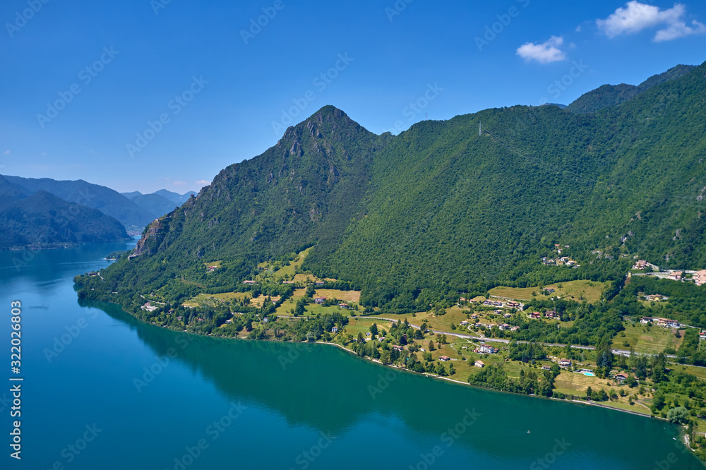 Panoramic view of the mountains and Lake Idro.  Reflection in the water of the mountains, trees, blue sky. Aerial view, drone photo