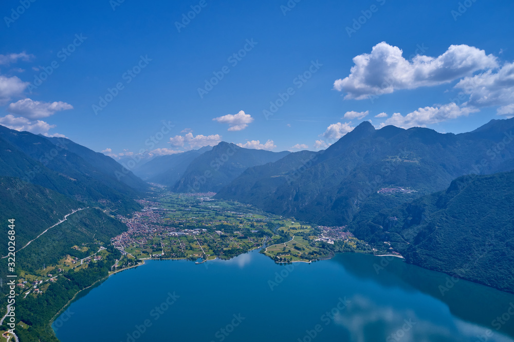 Panoramic view of the mountains and Lake Idro.  Reflection in the water of the mountains, trees, blue sky. Aerial view, drone photo