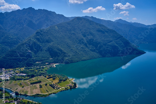 Fototapeta Naklejka Na Ścianę i Meble -  Panoramic view of the mountains and Lake Idro.  Reflection in the water of the mountains, trees, blue sky. Aerial view, drone photo