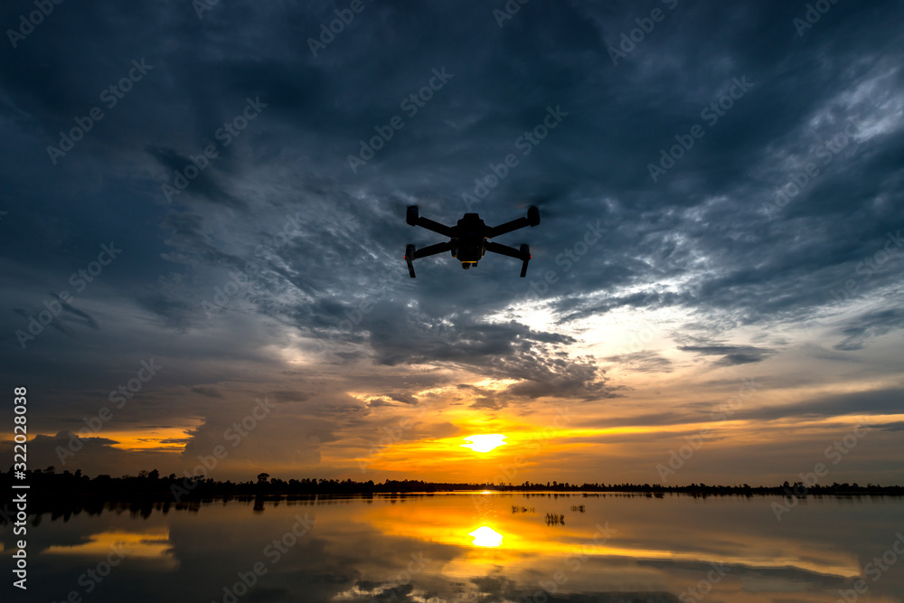 drone quadcopter with digital camera flying at sunset.Dark Flying drone and cloud sunrise sky. drone quadcopter with digital camera flying at sunset.Dark Flying drone and cloud sunrise sky.