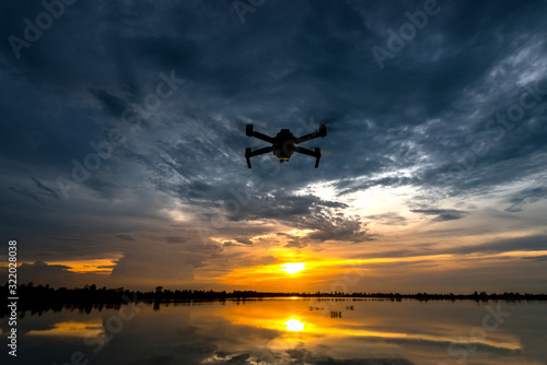 drone quadcopter with digital camera flying at sunset.Dark Flying drone and cloud sunrise sky. © noon@photo