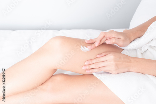 Woman applying legs cream lotion   Hygiene skin body care concept..