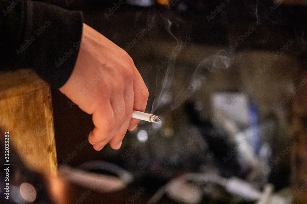 Male hand holding a smoking cigarette Male hand holding a smoking cigarette
