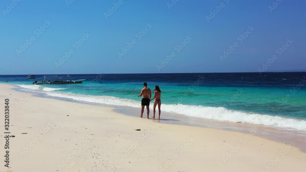 Happy couple on vacation trip, exploring exotic beach with white sand washed by waves of blue turquoise sea in Malaysia Happy couple on vacation trip, exploring exotic beach with white sand washed by waves of blue turquoise sea in Malaysia