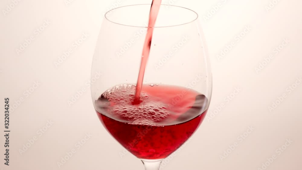 Red wine pouring from bottle into goblet over white background. Rose wine pour into glass. Wineglass Red wine pouring from bottle into goblet over white background. Rose wine pour into glass. Wineglass