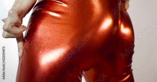 Extreme close up  shot of the hand of girl in a tight  fitting shiny red zentai suit, stroking herself with finger with manicure. Isolated on  white studio background. 4k 50 fps slow motion photo
