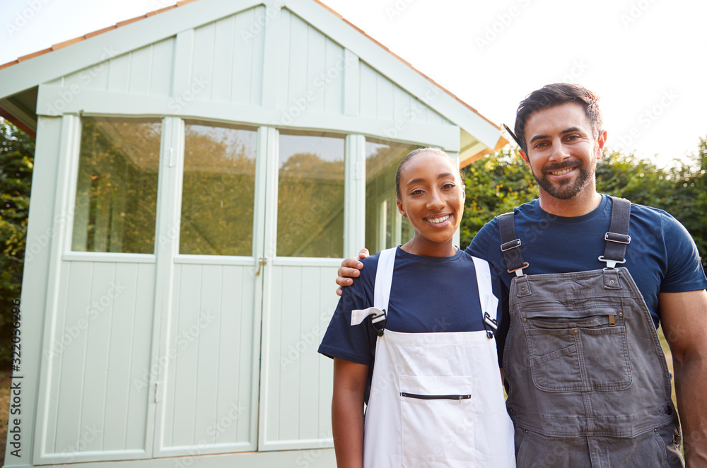 Portrait Of Proud Couple Standing In Front Of Completed Outdoor Summerhouse In Garden Portrait Of Proud Couple Standing In Front Of Completed Outdoor Summerhouse In Garden