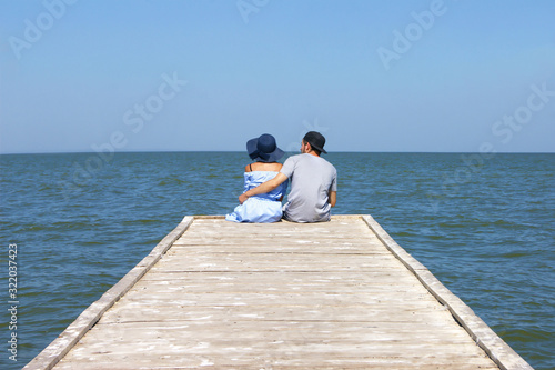 Loving couple sitting in an embrace on the edge of the pier.