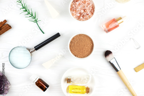 Homemade spa cosmetic set with salt, clay mask and oil on white wooden background. Copy space. Flat lay style.