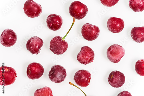group of frozen cherries on a white background throughout the photo. the view from the top. pattern. close up. ice crystals on the fruit.