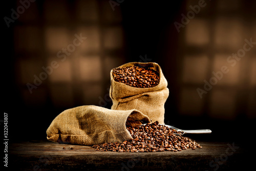 Fresh coffee grains in sack and dark interior with sadows.Copy space for your decoration. 