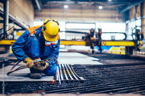 фотографія Worker cutting metal, steel with acetylene torch in big factory.