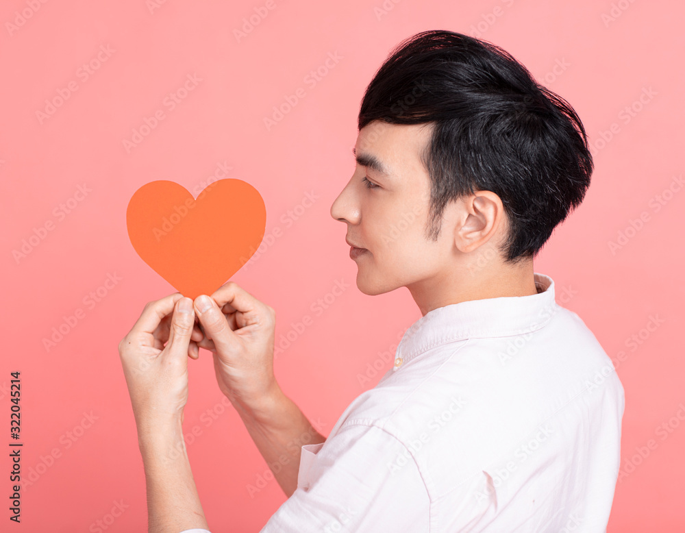 Happy young man showing red paper hearts and celebrating valentines day Happy young man showing red paper hearts and celebrating valentines day