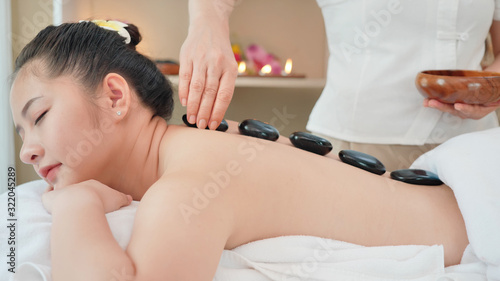 Young Asian woman getting spa massage with hot stone massage at beauty spa salon. Relaxing massage for health