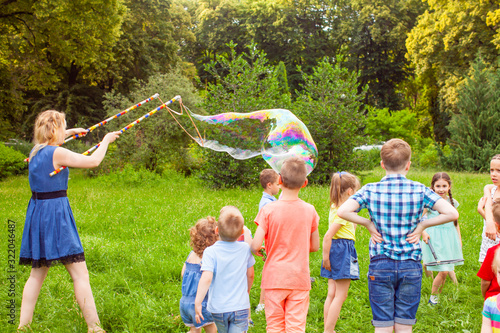 Tablou pe pânză Young woman entertains children with soap bubbles