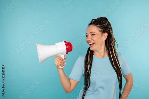 Portrait of laughting woman having fun with megaphone isolated over the blue studio