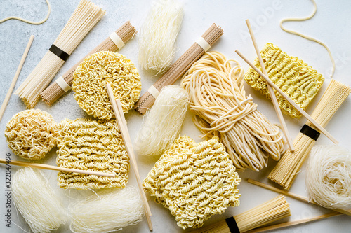 Variety of uncooked asian noodles on light background, closeup view