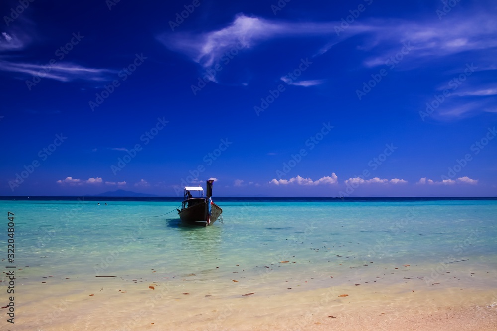 Panoramic view from sand beach over shallow turquoise water and isolated thai long-tail boat into endless horizon with blue sky - Ko Phi Phi, Thailand Panoramic view from sand beach over shallow turquoise water and isolated thai long-tail boat into endless horizon with blue sky - Ko Phi Phi, Thailand