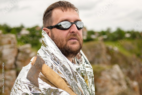 Photography an oddball in glasses with an axe in his hand and dressed in foil against the sk