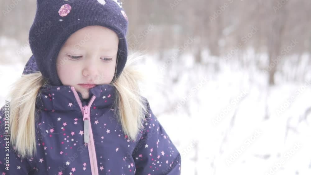 Sad little girl in the background of the snowy winter forest. Close-up of a child in a hat Sad little girl in the background of the snowy winter forest. Close-up of a child in a hat