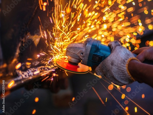Soft of focus. worker grinding cutting metal sheet with grinder machine overwrites the master of welding seams angle grinder and sparks. 