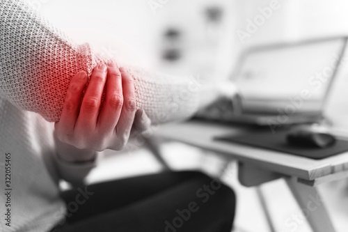 Woman working on a laptop and having elbow pain.