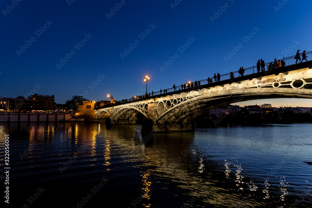 Triana bridge (Isabel II bridge) over Guadalquivir river at night, Seville, Spain