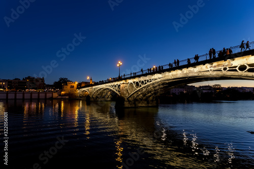 Triana bridge (Isabel II bridge) over Guadalquivir river at night, Seville, Spain