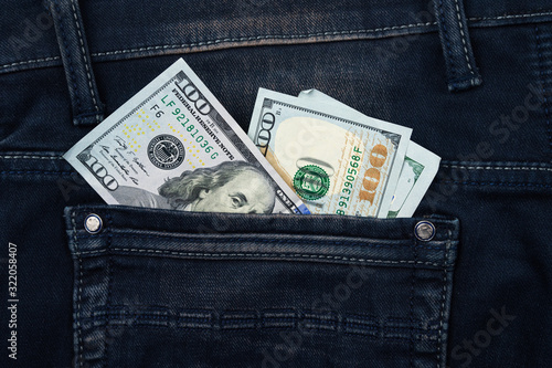 One hundred dollar banknote money in pocket jeans pants background texture. 100 dollar bill close up