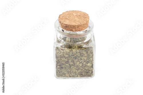 dried lovage herb in a glass jar isolated on white background. spices and food ingredients