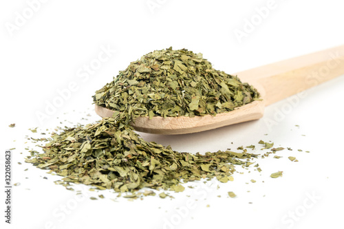 dried lovage herb in wooden spoon isolated on white background. spices and food ingredients. spices and food ingredients