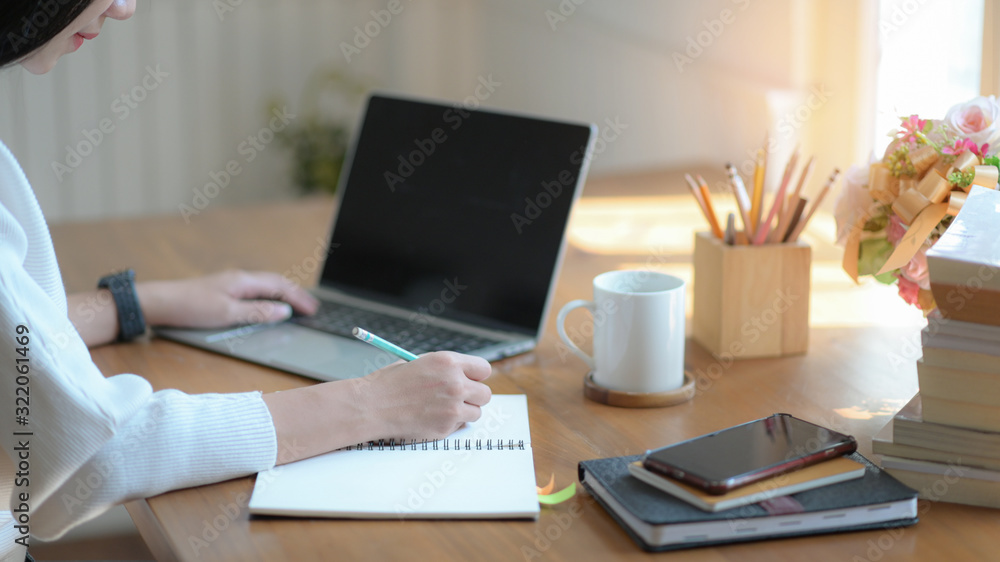 Young businesswomen are taking notes and using a blank screen laptop in a modern office. Young businesswomen are taking notes and using a blank screen laptop in a modern office.