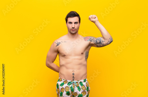 Canvastavla young handsome man feeling serious, strong and rebellious, raising fist up, prot