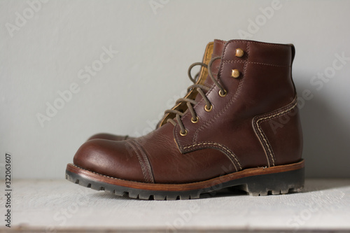 ฺBrown leather shoes with vintage camera on a wooden floor.Brown vintage leather boots aligned selective focus.Men leather shoes 