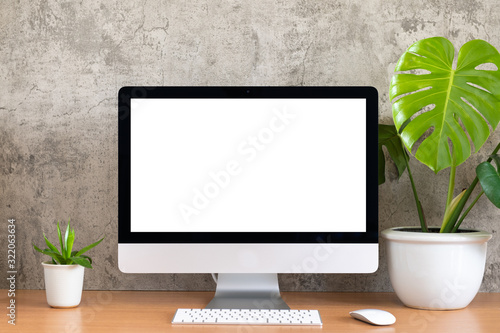 Blank screen of All in one computer, keyboard, mouse, monstera pot and small plant pot on wooden table