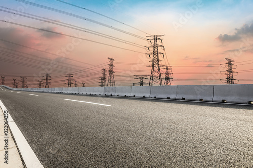 High voltage power tower and empty asphalt road at dusk © zhao dongfang