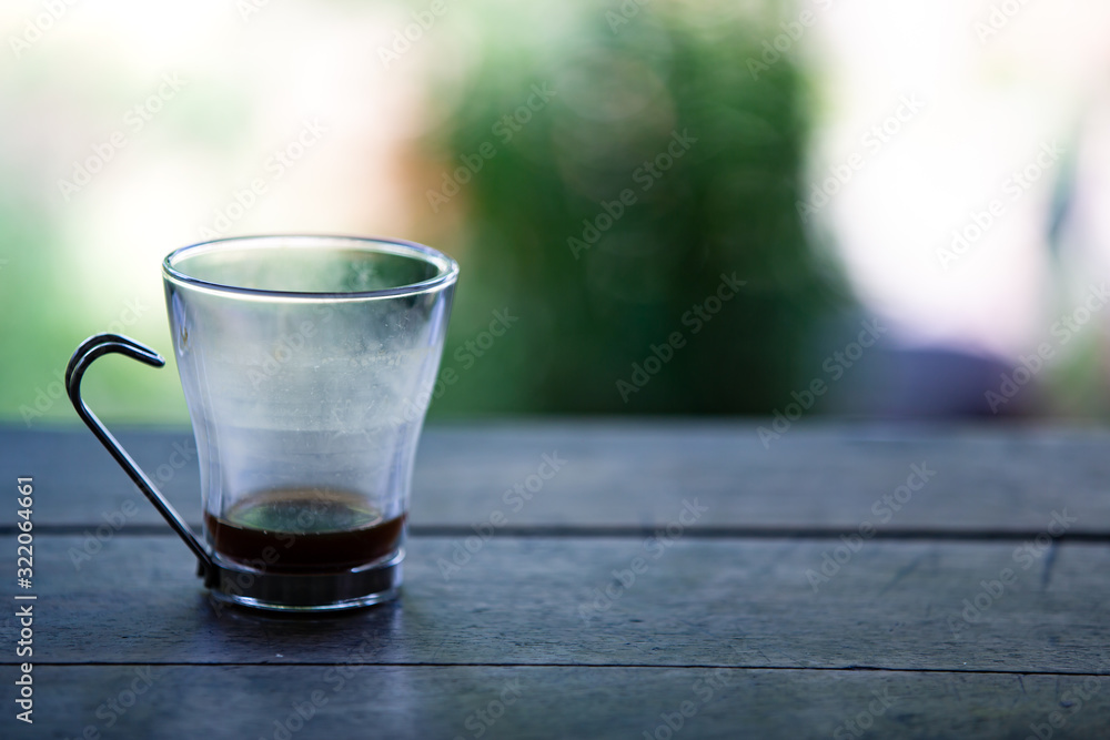 Coffee glasses cup with coffee stains stuck on them, then after drinking it on wooden table in bokeh blurred green garden background, Close up shot, Selective focus Coffee glasses cup with coffee stains stuck on them, then after drinking it on wooden table in bokeh blurred green garden background, Close up shot, Selective focus